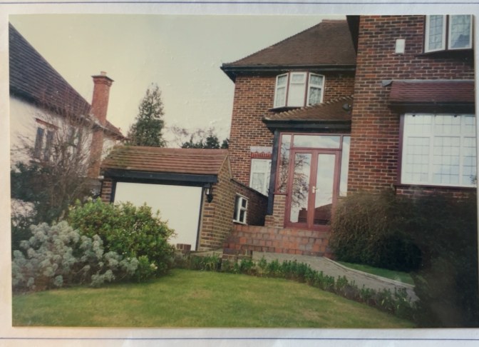 Original archive photograph: the new porch entrance and garage at the Coulsdon house seen from the lawn, the tiled porch roof set against the chimney and the main roof of the house