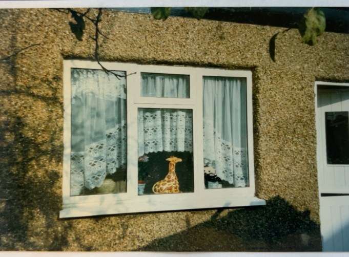 Original archive photograph: the re-set double-glazed window in the pebbledashed wall on completion, with net curtains and a china ornament on the sill