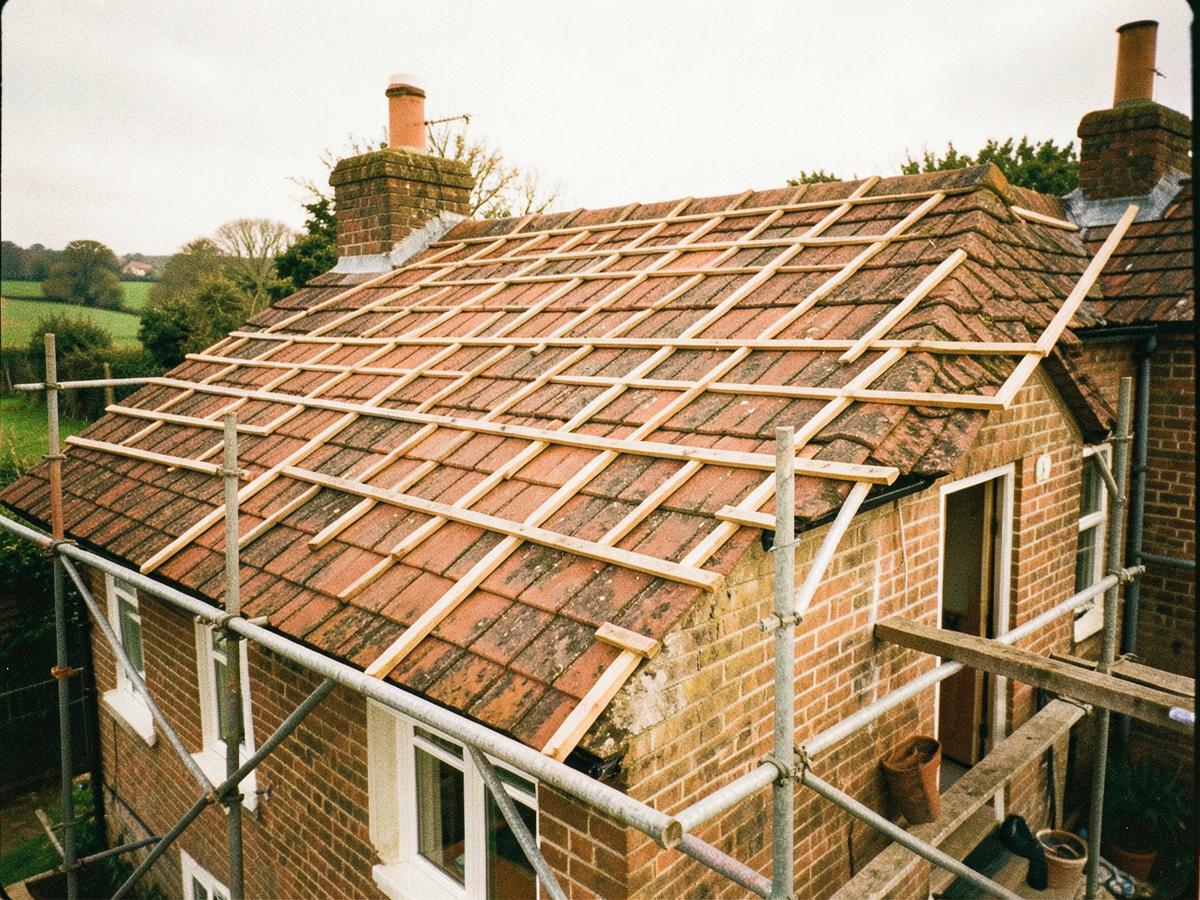 Archive photograph of a clay tile roof being re-laid, with battens exposed