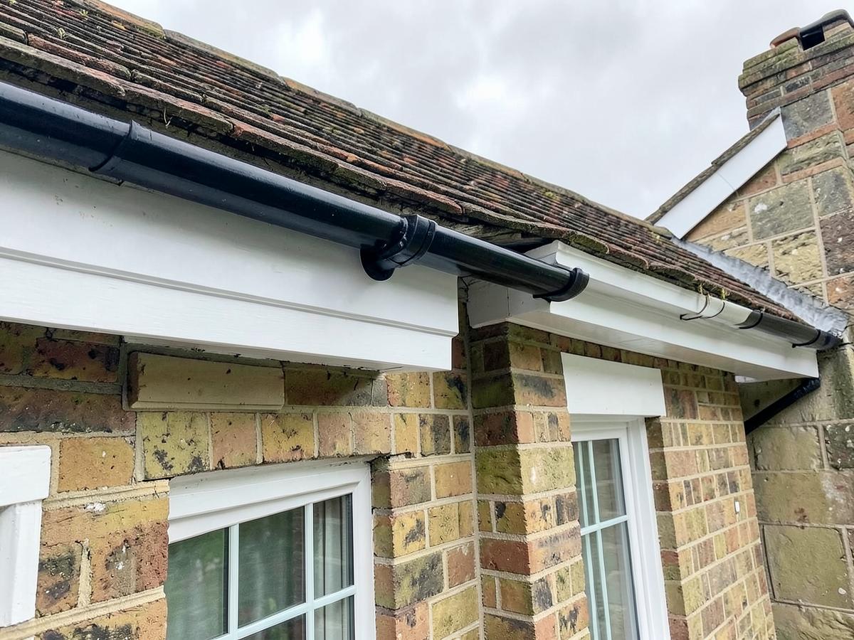 New white fascias and black guttering on the edge of a clay-tiled Kent cottage roof